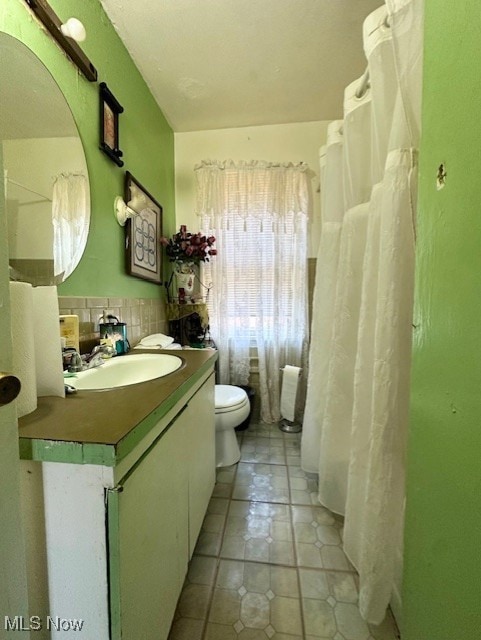 Full bathroom featuring vanity, light tile patterned floors, a shower with shower curtain, and tile walls