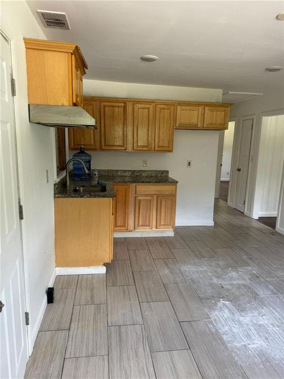 Kitchen featuring dark stone counters, brown cabinets, and wood tiled floors