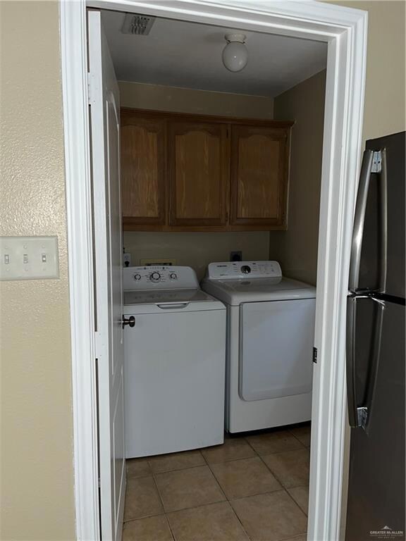 Washroom featuring cabinet space, separate washer and dryer, and light tile patterned floors