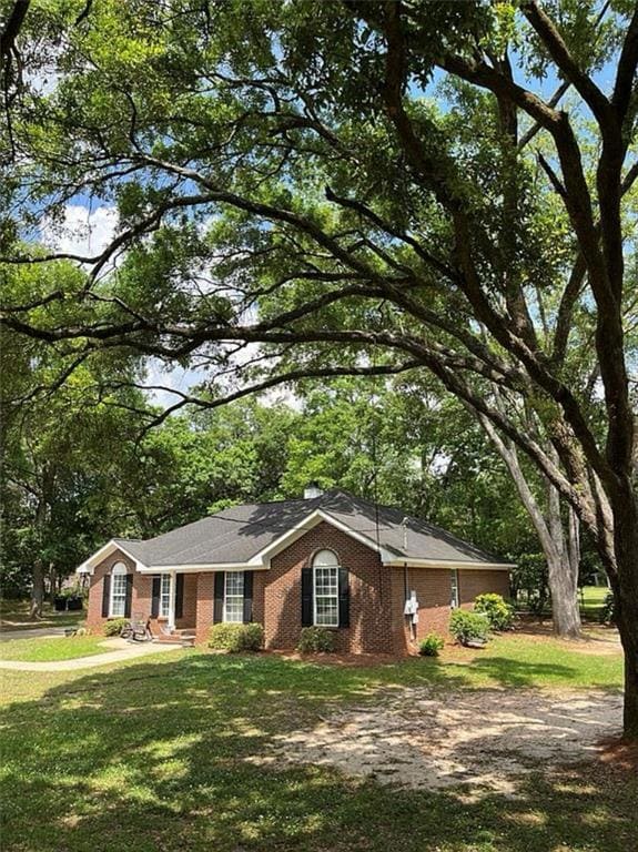 Ranch-style house with brick siding, a front lawn, and view of scattered trees