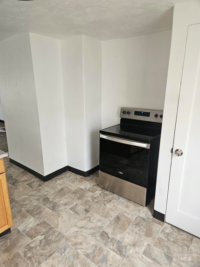 Kitchen featuring stainless steel electric stove and stone finish floors