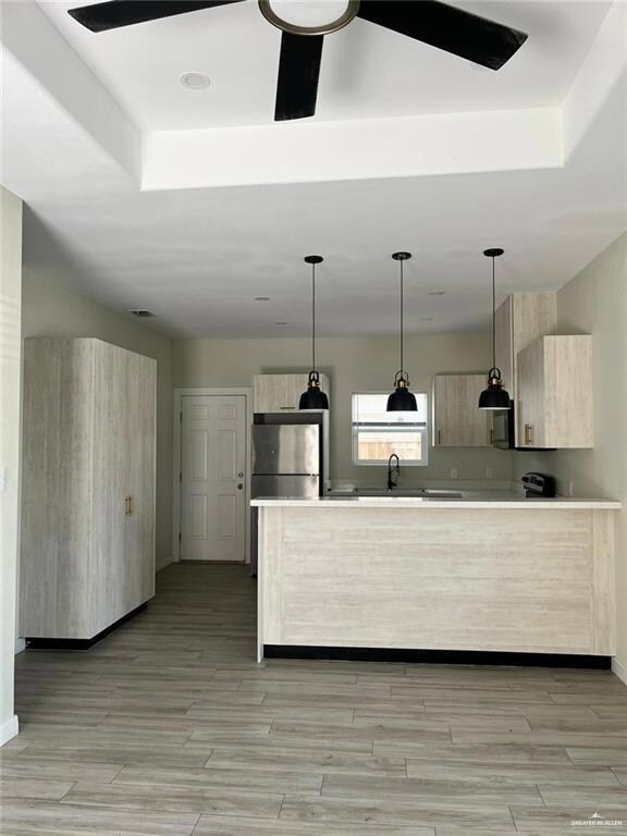 Kitchen with freestanding refrigerator, modern cabinets, a raised ceiling, and light countertops