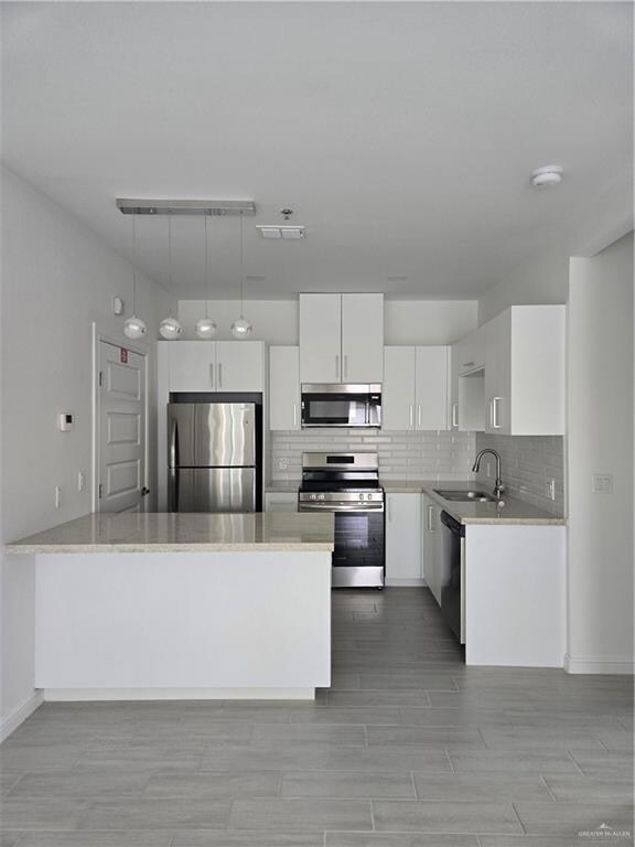 Kitchen with fridge, dishwashing machine, tasteful backsplash, a sink, and range