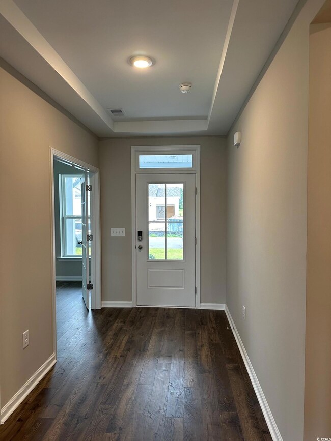 Entryway with dark wood-type flooring and a raised