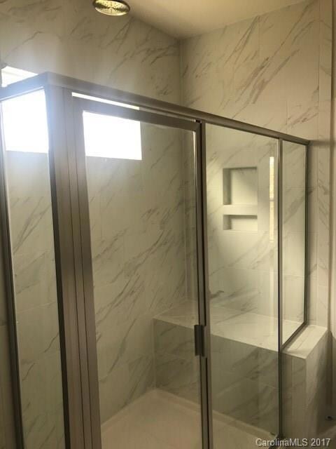 Oversized tiled shower with bench in owner's bath complete with dual shower heads!