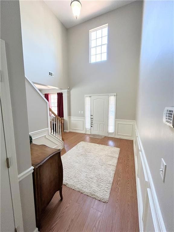 Foyer featuring a high ceiling, a decorative wall, healthy amount of natural light, wood finished floors, and stairs