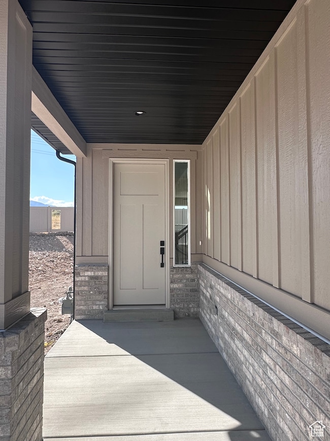 Doorway to property with board and batten siding, brick siding, and a patio area