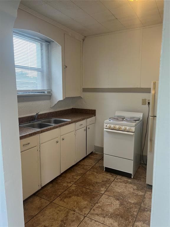 Kitchen featuring fridge, range, dark countertops,