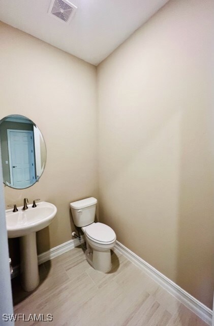 Half bathroom with baseboards and toilet