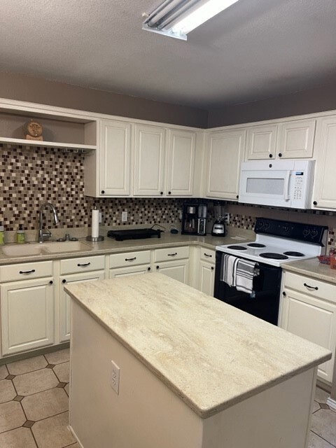 Kitchen with open shelves, a center island, white cabinetry, a sink, and range