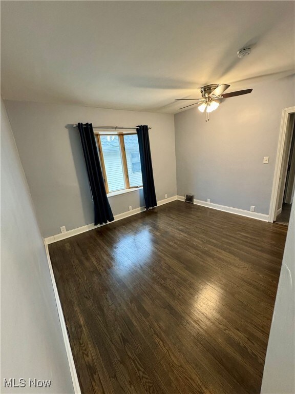 Unfurnished room with ceiling fan and dark hardwood / wood-style floors