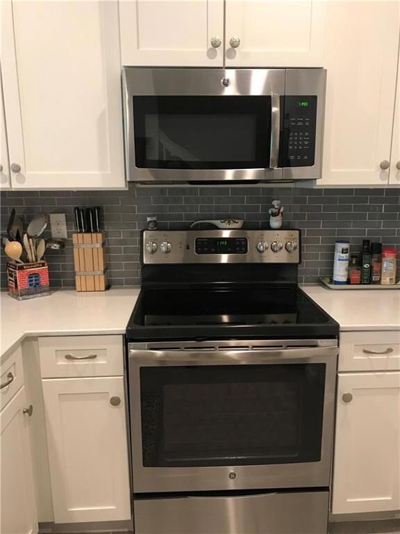 Stainless steel appliances and grey glass subway tile backsplash
