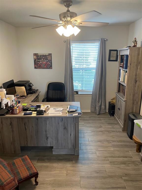 Office area with ceiling fan and light wood-type f
