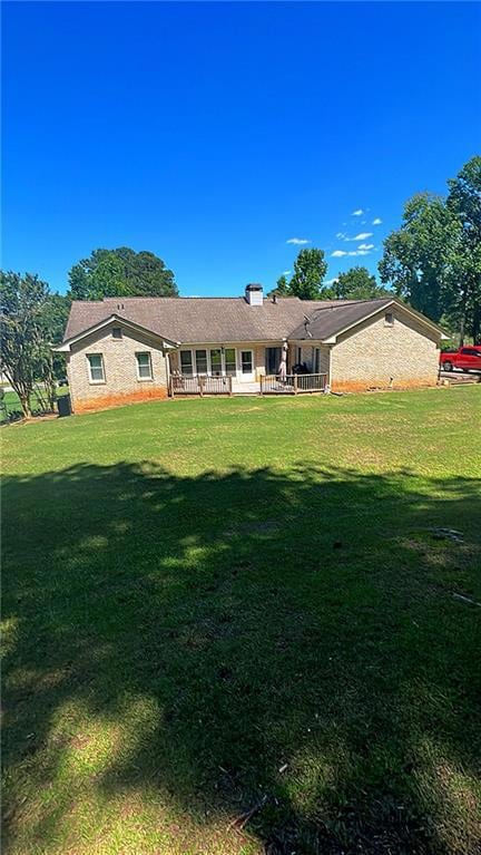 Back of property with a yard, a porch, and a chimney