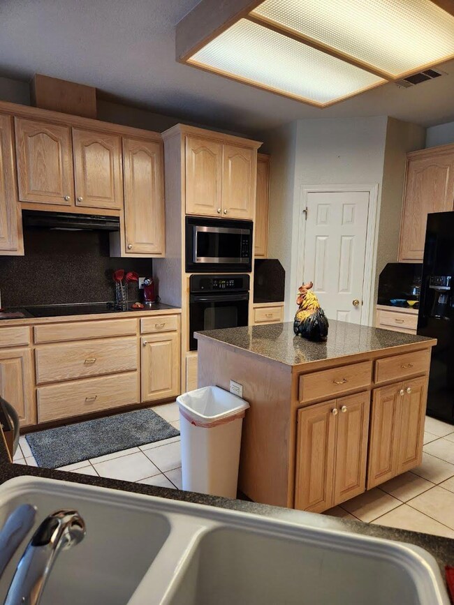 Kitchen featuring black appliances, light tile pa