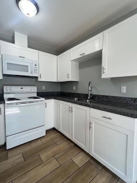 Kitchen featuring dark hardwood / wood-style floors, sink, white cabinetry, and stove