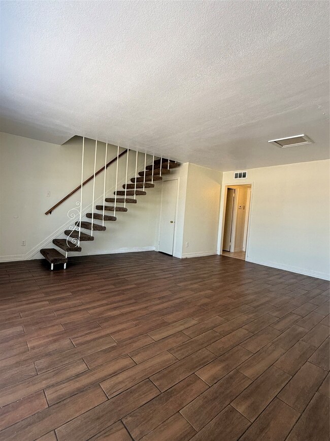 two-story townhouse with a mix of brick and siding exterior. It features a small front yard with a concrete path leading to the entrance. Large windows on the second floor and a neatly landscaped area enhance its curb appeal.