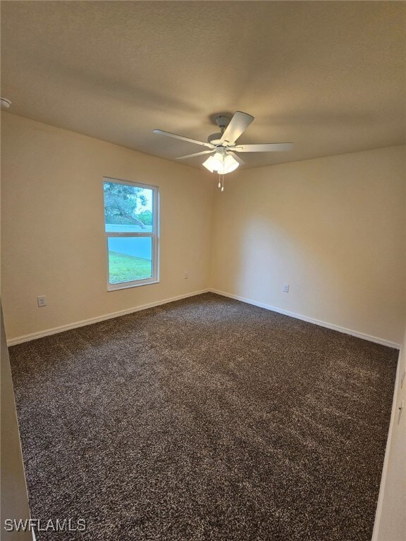 Empty room with a ceiling fan and dark carpet