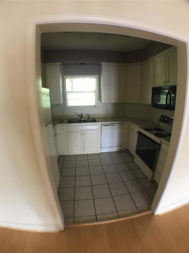Kitchen with wood finished floors, white cabinetr