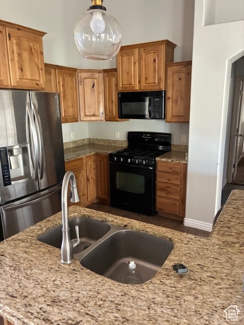 Kitchen with black appliances, light stone counters, and brown cabinetry