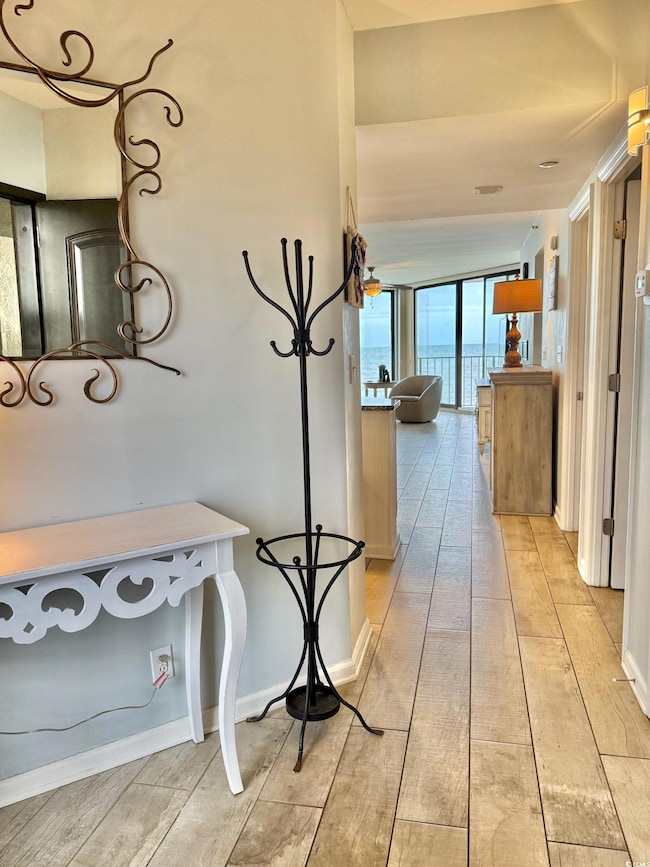 Hallway with a wall of windows, light wood-type flooring, and a water view