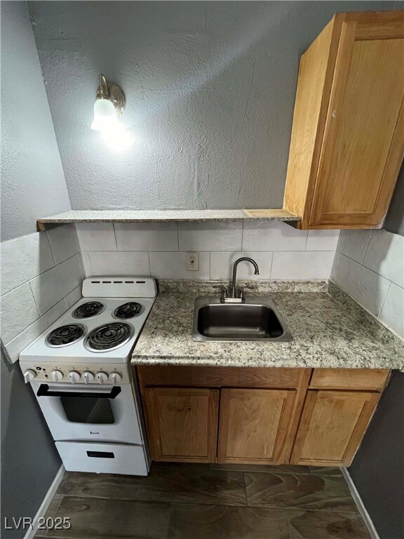 Kitchen with white electric range, a sink, tastefu