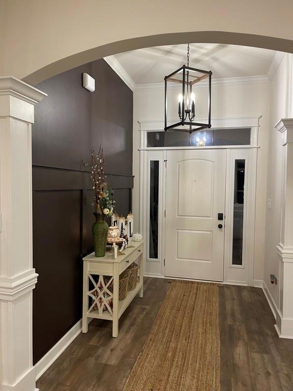 Foyer with dark wood-style floors, ornamental molding, ornate columns, and arched walkways