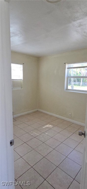 Empty room featuring plenty of natural light and light tile patterned floors