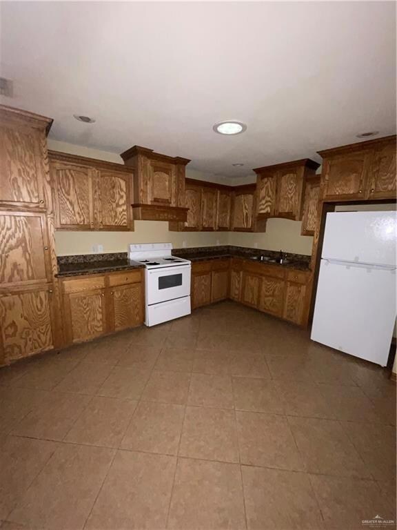 Kitchen with refrigerator, sink, range, and tile floors
