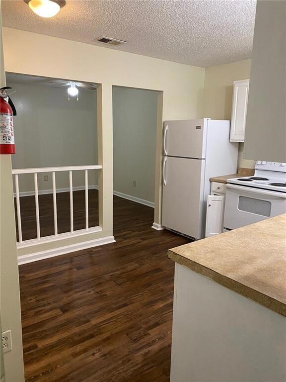 Kitchen with dark wood-type flooring, a textured c