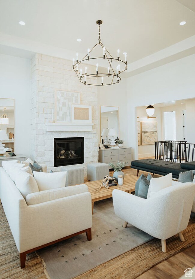 Living room with a large fireplace, a chandelier, recessed lighting, and wood finished floors
