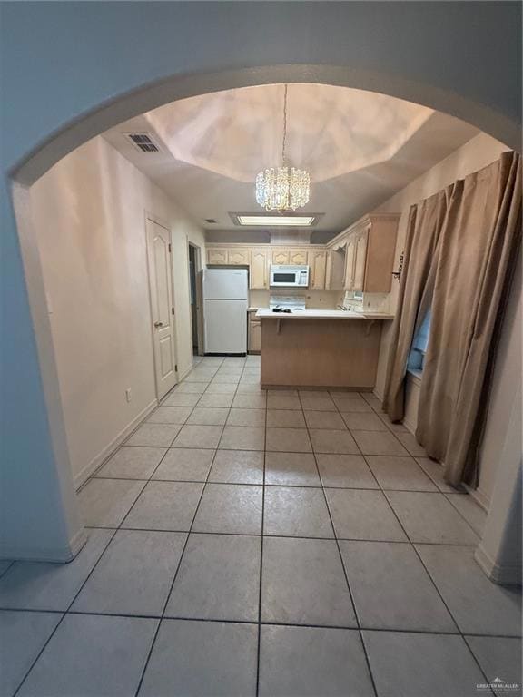 Kitchen with fridge, light tile patterned floors, a chandelier, arched walkways, and a peninsula