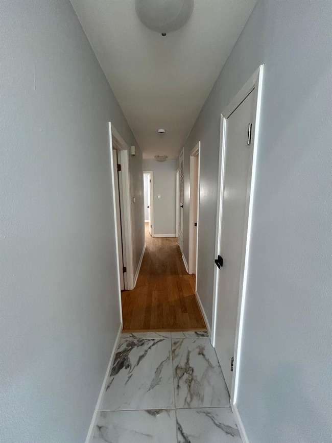 Hallway with marble finish flooring and baseboards