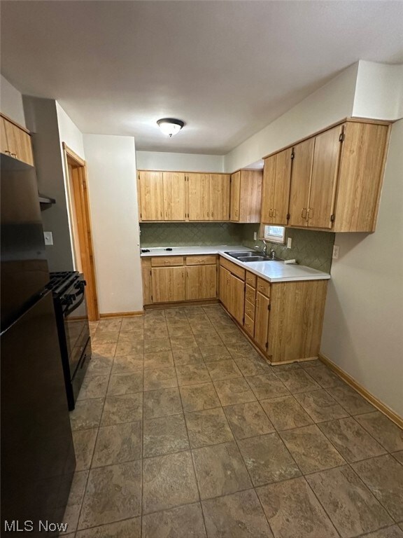 Kitchen with black appliances, dark tile flooring, sink, and backsplash