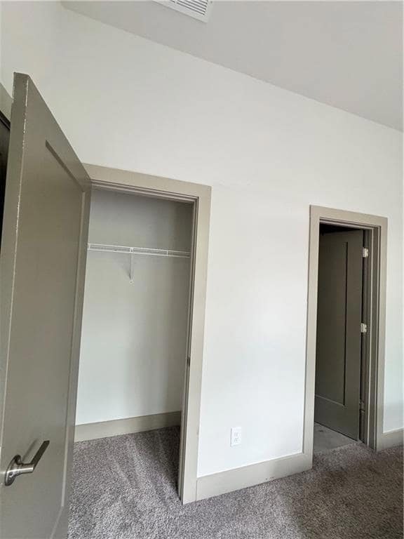 Unfurnished bedroom with carpet, a closet, and bas