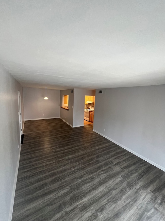 Unfurnished room with dark wood finished floors and baseboards