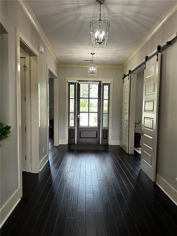 Long entryway with chandeliers, dark wood-style floors and barn door entry to the second bedroom