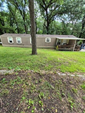 View of front of property featuring a front yard and view of scattered trees