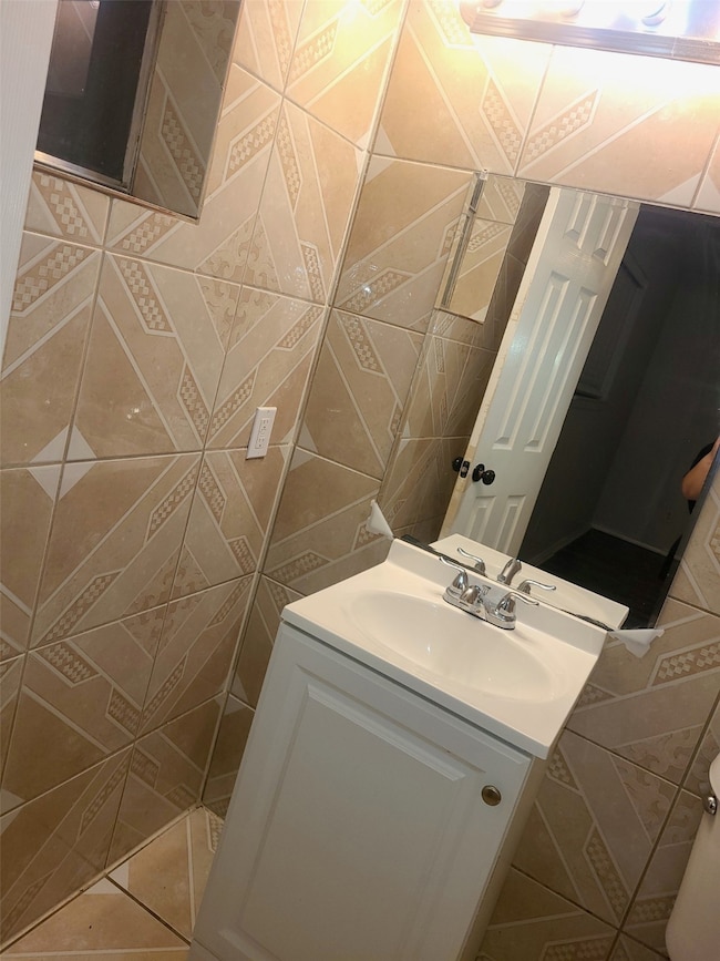 Half bath featuring vanity and tile walls