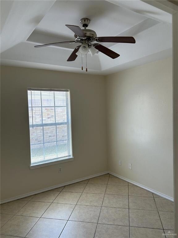 Spare room featuring light tile patterned flooring, a ceiling fan, and baseboards