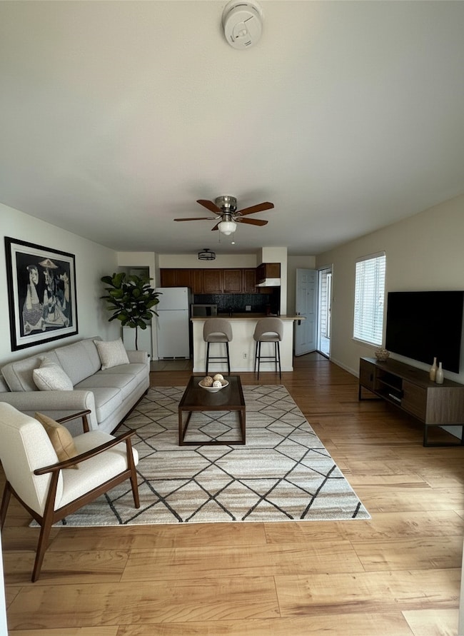 Living room with light wood-type flooring and ceiling fan