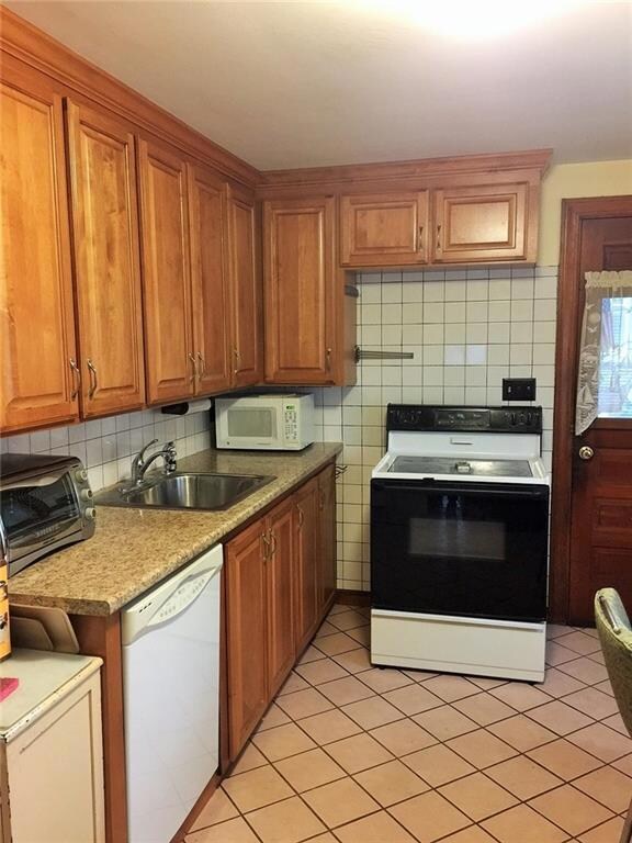 Tiled kitchen with maple cabinetry.