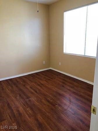 Empty room featuring dark wood-type flooring and baseboards