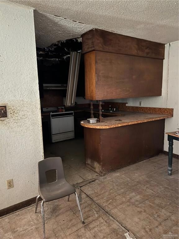 Kitchen with a textured ceiling, stove, and exhaust hood