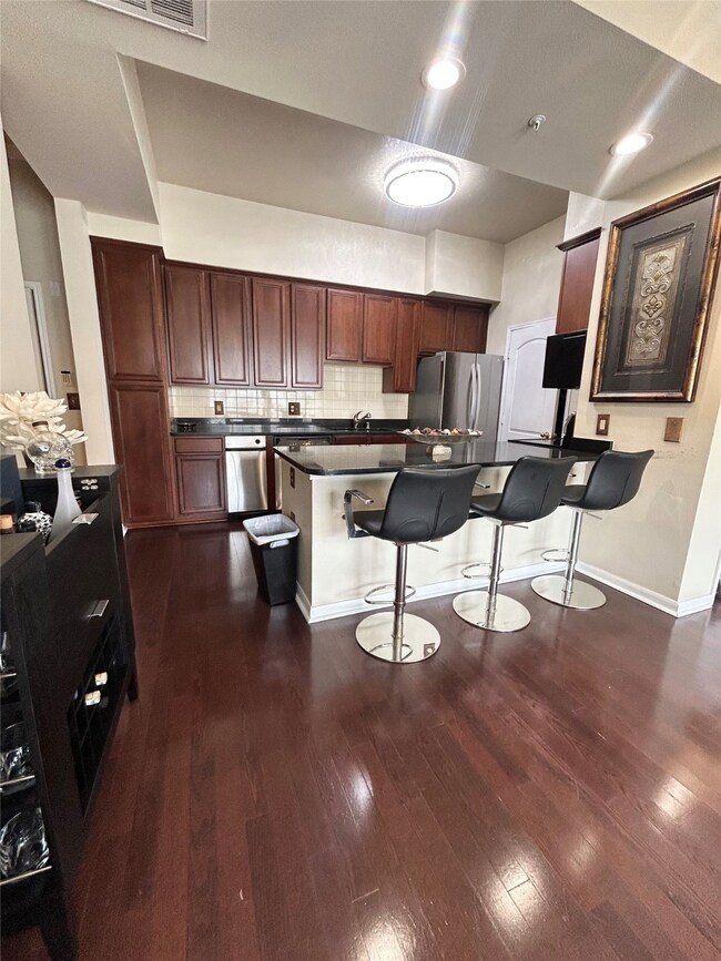 Kitchen with dark wood finished floors, backsplash, a kitchen bar, a peninsula, and freestanding refrigerator