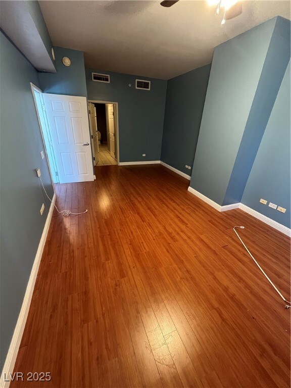 Unfurnished room with hardwood / wood-style floors, baseboards, and a ceiling fan