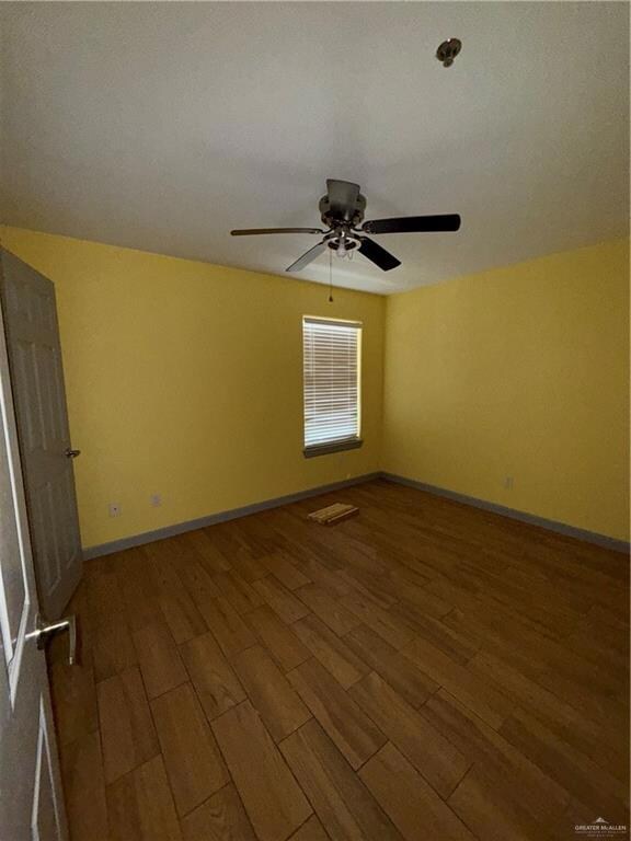 Bathroom with vanity, wood finished floors, toilet, tiled shower, and baseboards
