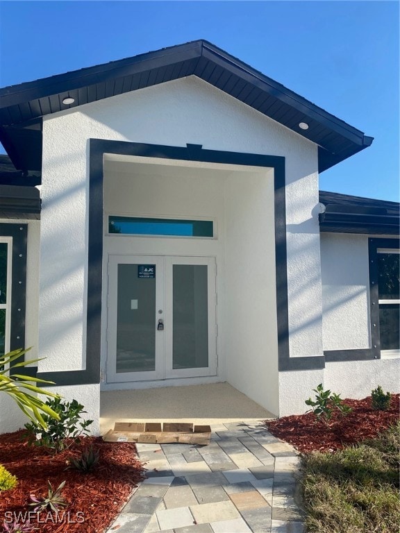 View of exterior entry with french doors and stucc