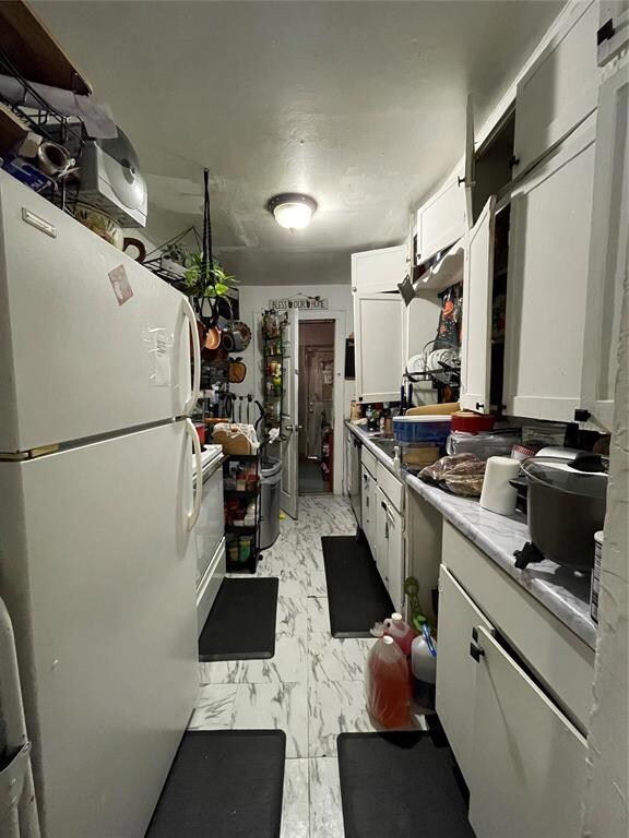 Kitchen with refrigerator, white cabinets, and lig