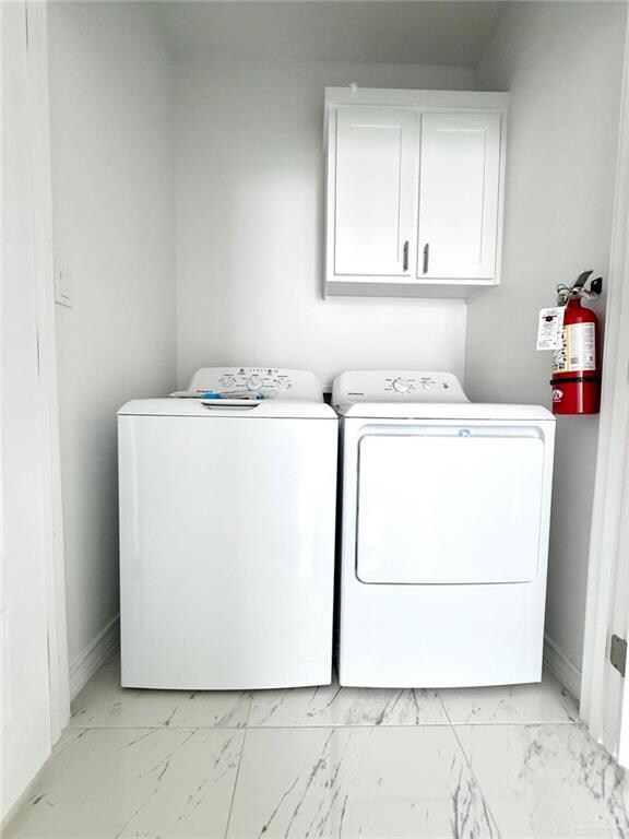 Laundry room featuring light marble finish flooring, cabinet space, and washer and clothes dryer
